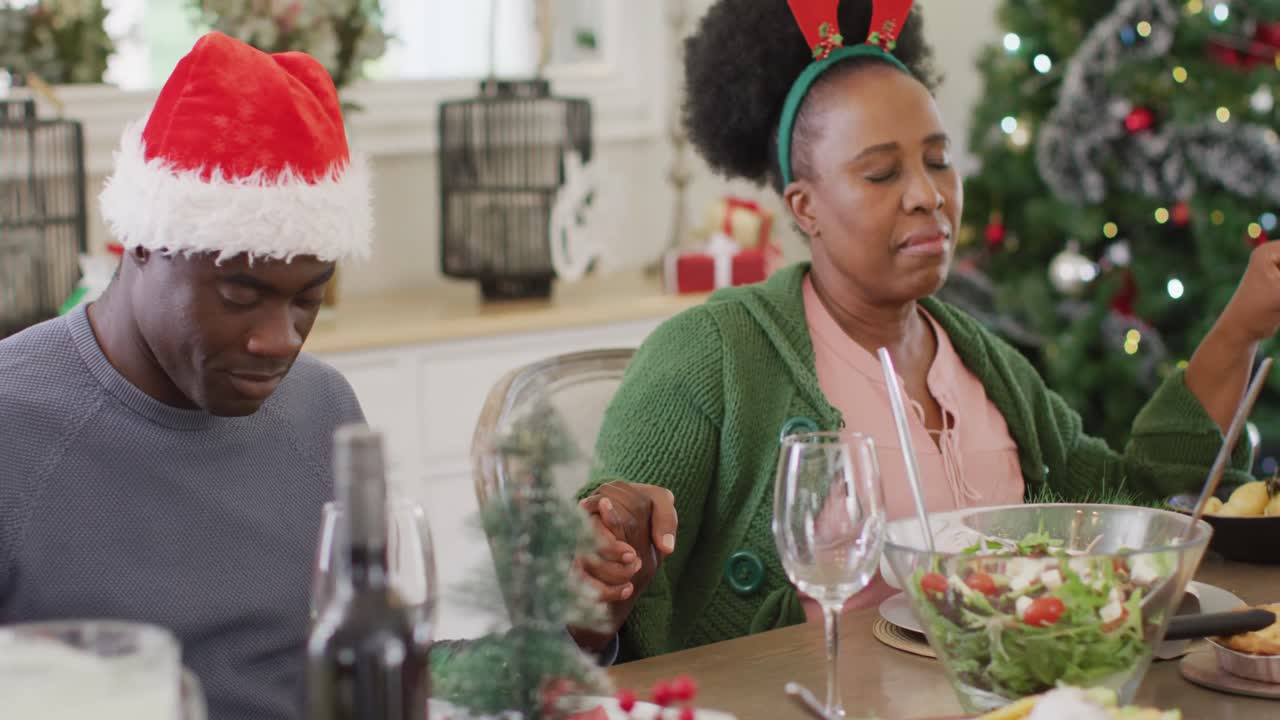 familia afroamericana orando antes de la cena de navidad