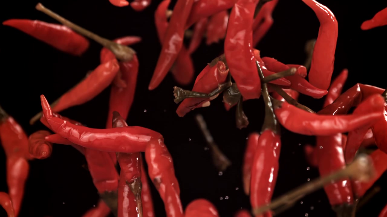 Fresh Red Chili Peppers Falling in Slow Motion on Black Background