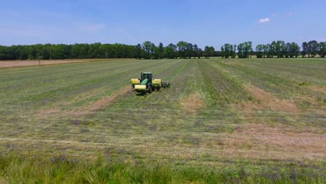 tiro de dron de marcha atrás del tractor cosechando un campo verde