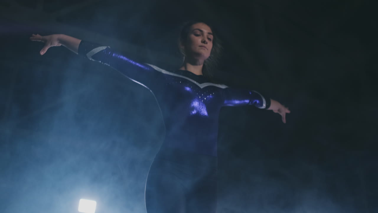 en cámara lenta en el humo, una atleta de pie con los brazos levantados después de realizar ejercicios. gesto de bienvenida con las manos.