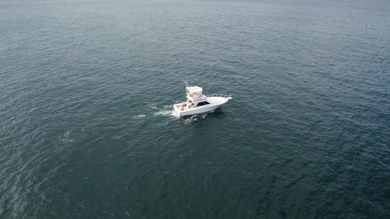 Aerial view of fishing boat sailing calmly on deep ocean waters during sunny day.