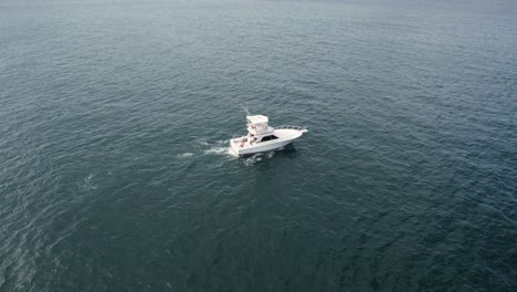 aerial view of fishing boat sailing calmly on deep ocean waters during sunny day.
