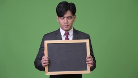 젊은 잘생긴 아시아 사업가 블랙보드를 보여줍니다.