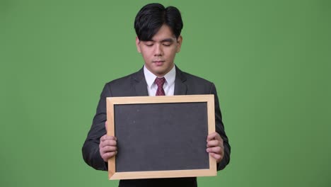 young handsome asian businessman showing blackboard