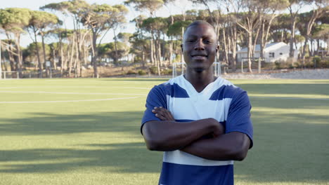 standing on soccer field, african american man in sportswear crossing arms and smiling, copy space