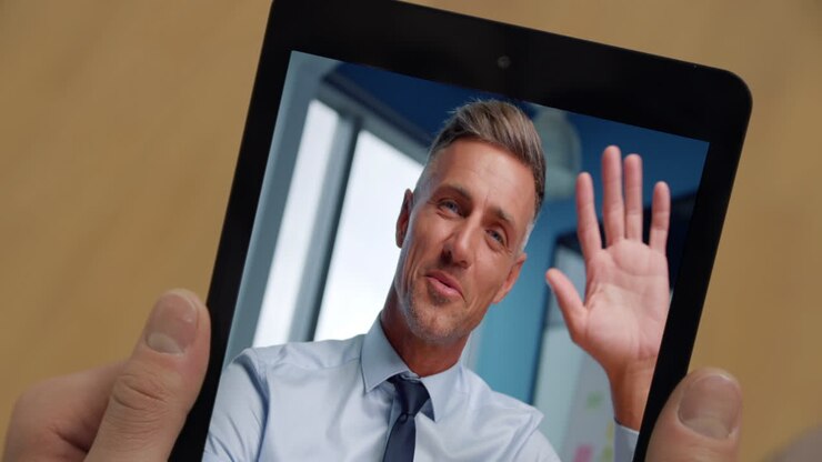 Primo piano di un responsabile che saluta durante una videochiamata con un cliente sconosciuto tramite tablet a casa
