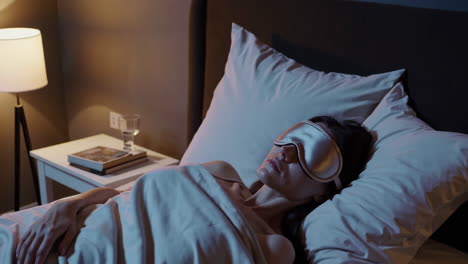 woman sleeping peacefully with a sleep mask in bed at night