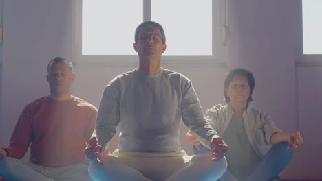 senior people meditating in lotus position in gym