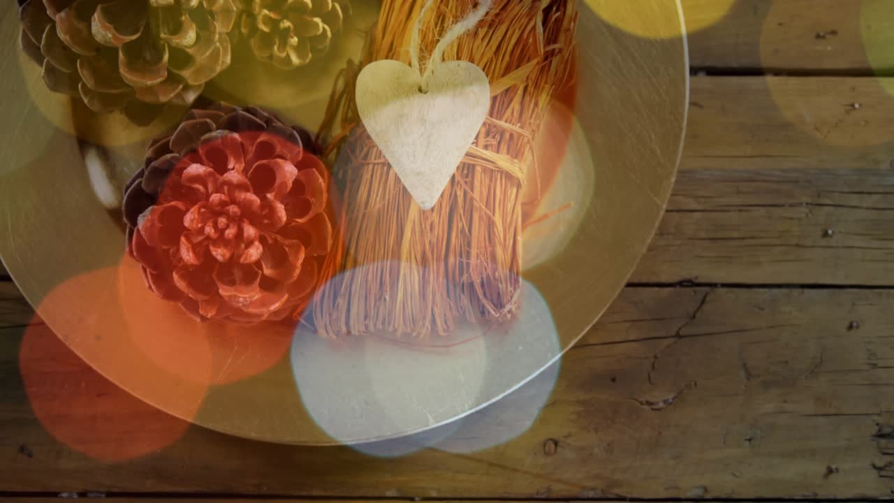 Shifting bokeh lights revealing round dish with pine cones and heart tag, showing rustic decor