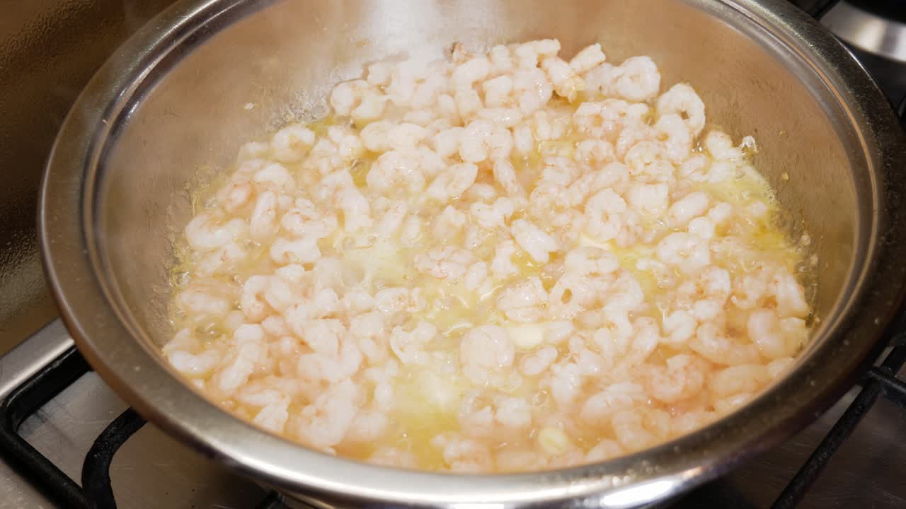 camarones pequeños frescos cocinados con salsa de mantequilla en una olla caliente plateada