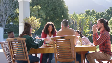 happy diverse male and female friends serving thanksgiving celebration meal in sunny garden