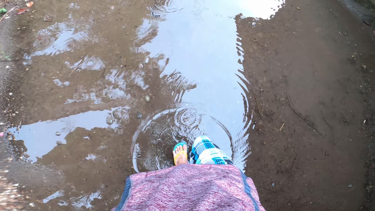 los pies de la persona caminando en el charco de agua de lluvia en un día lluvioso - tiro pov