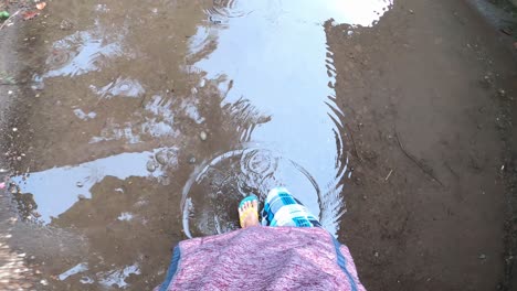 Person's-Feet-Walking-In-The-Puddle-Of-Rainwater-On-A-Rainy-Day---POV-shot