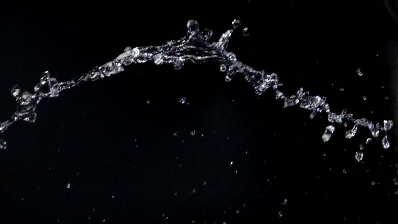 Vandstænk og sprøjt i slowmotion på sort baggrund