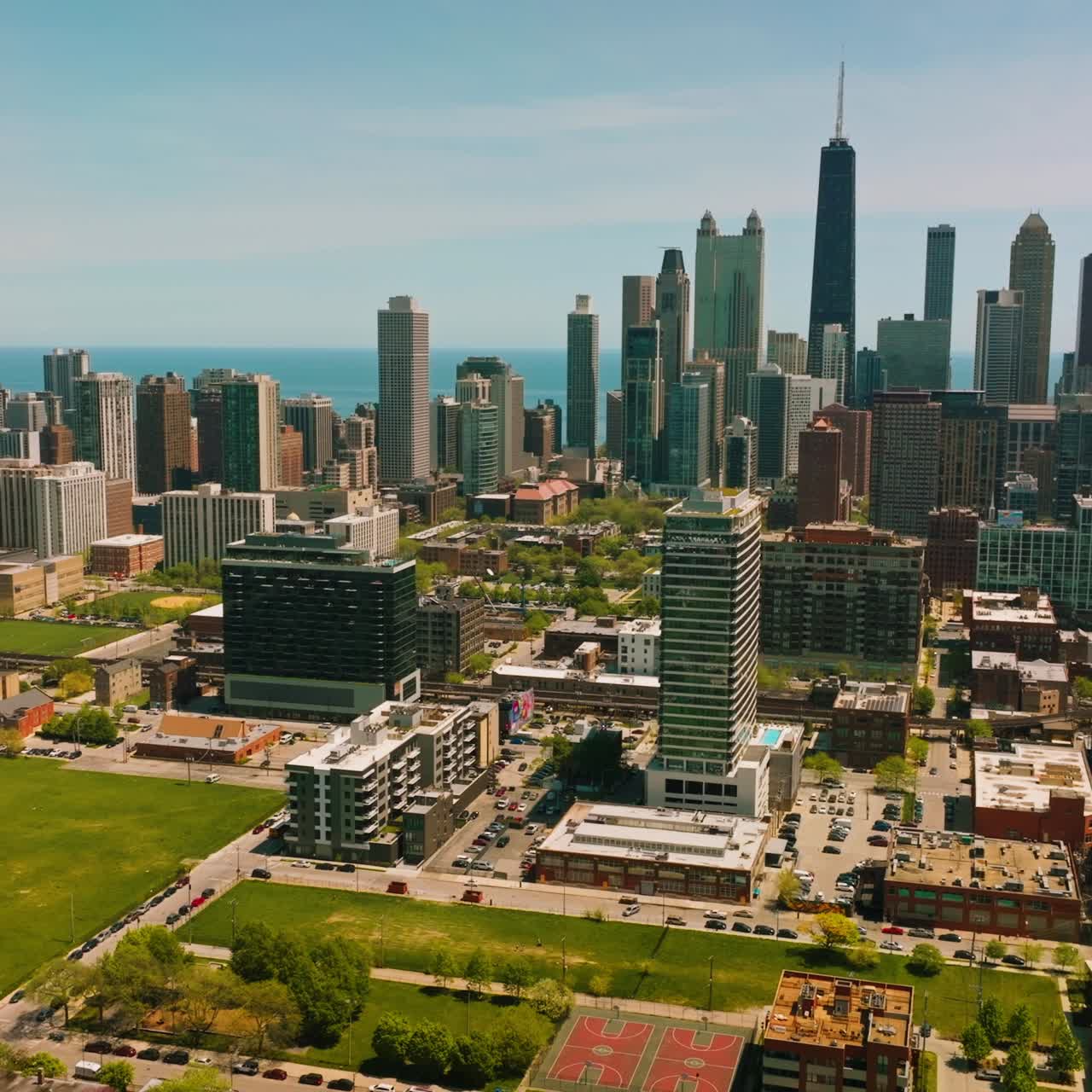 Green areas among the buildings of modern Chicago. Cars moving along numerous roads. Skyscrapers at backdrop
