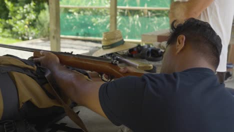 man aiming wooden shotgun at firing range for target practice