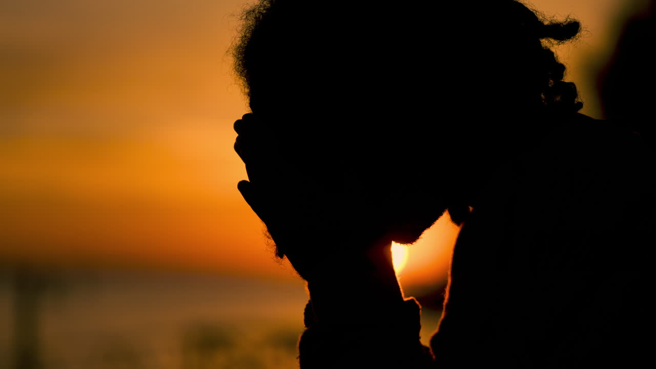 Silhouette of a Person with Dreadlocks at Sunset