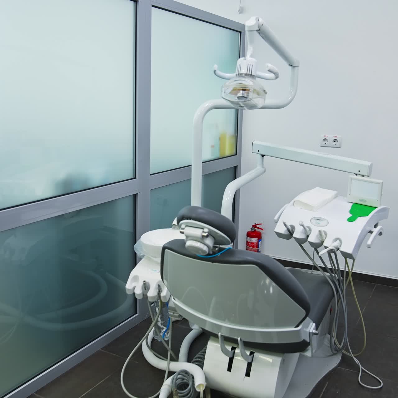 Minimalistic working place of a modern dentist. Light big room divided into several working areas. Comfortable armchair for patients of dentistry professionals