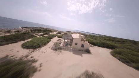 fpv drone shot over rocky beaches covered with green vegetation in faro de s'estalella, mallorca, balearic islands, spain on a sunny day