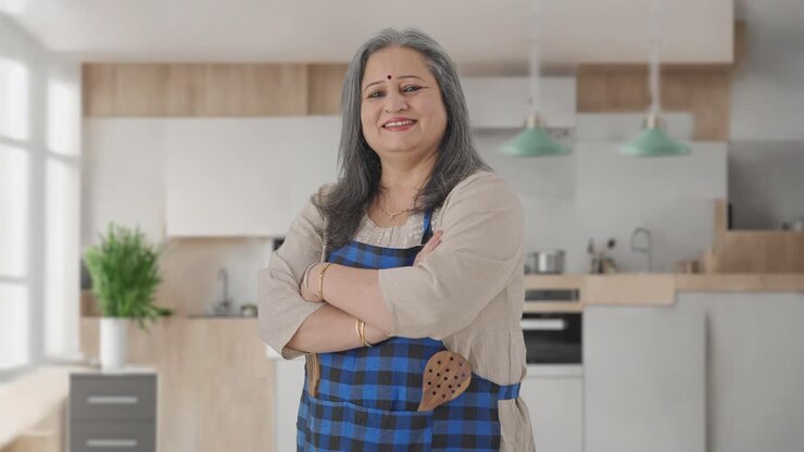 retrato de una feliz ama de casa india de edad avanzada de pie con las manos cruzadas