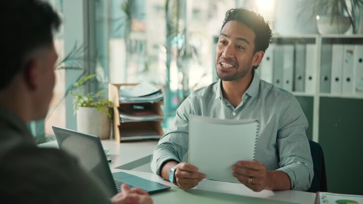 Smiling Man Discussing Paperwork in a Modern Office Interview