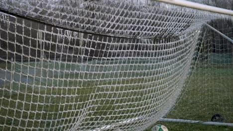 slow motion: a soccer ball slams an icy net of a soccer goal exploding shattered ice into the air