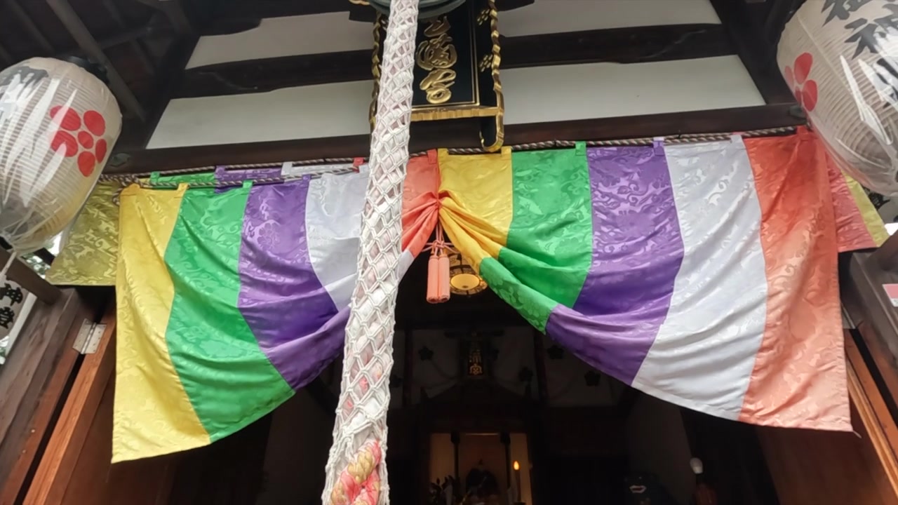Rope and bell at entrance of Kyoto temple with colorful banners and lanterns