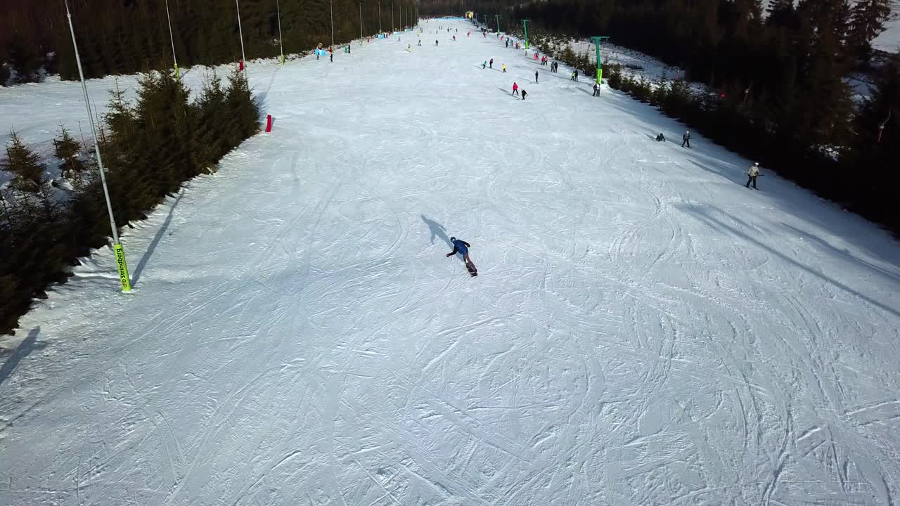 vista aérea de una persona haciendo snowboard cuesta abajo en la cumbre nevada de topolita, con un dron volando hacia adelante