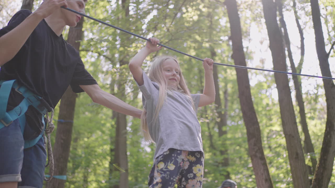 las niñas aprenden a caminar en teleféricos y superar acantilados y cruces de cuerda en un campamento de verano