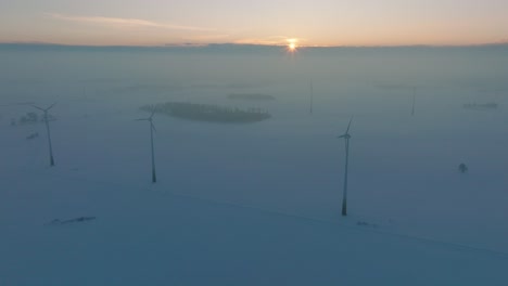 Luftbild-Von-Windkraftanlagen,-Die-Im-Windpark-Erneuerbare-Energie-Erzeugen,-Schneebedeckte-Landschaft-Mit-Nebel,-Sonniger-Winterabend-Mit-Goldenem-Stundenlicht,-Weites-Drohnenbild,-Das-Sich-Vorwärts-Bewegt