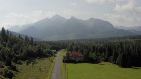 vista de los altos tatras en la carretera tatranska javorina en eslovaquia con casas aisladas y nubes de niebla - plano general