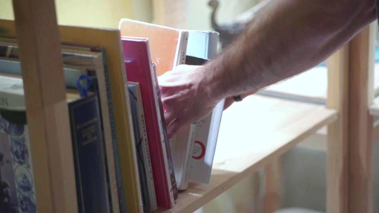 Man puts down returning books to library book shop. Education at university school. Male hands.