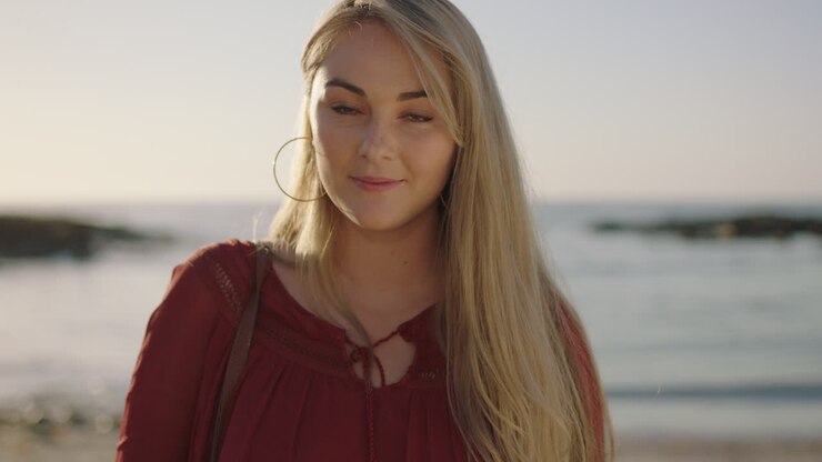 portrait en gros plan d'une jolie jeune femme blonde souriante flirtant confiante sur une plage ensoleillée au bord de la mer