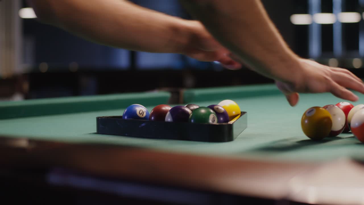Man setting up pool balls on a pool table.