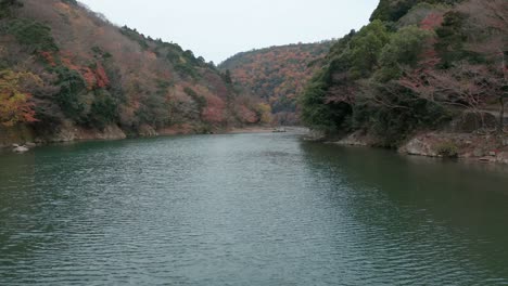 Katsura-River-at-Arashiyama,-Slow-Push-over-Calm-Waters-in-Autumn-Scene