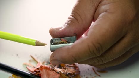 imágenes de manos afilando lentamente un lápiz y algunos lápices de colores con un sacapuntas de cuña