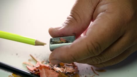 footage of hands slowly sharpening a pencil and some coloured pencils with a wedge pencil sharpener