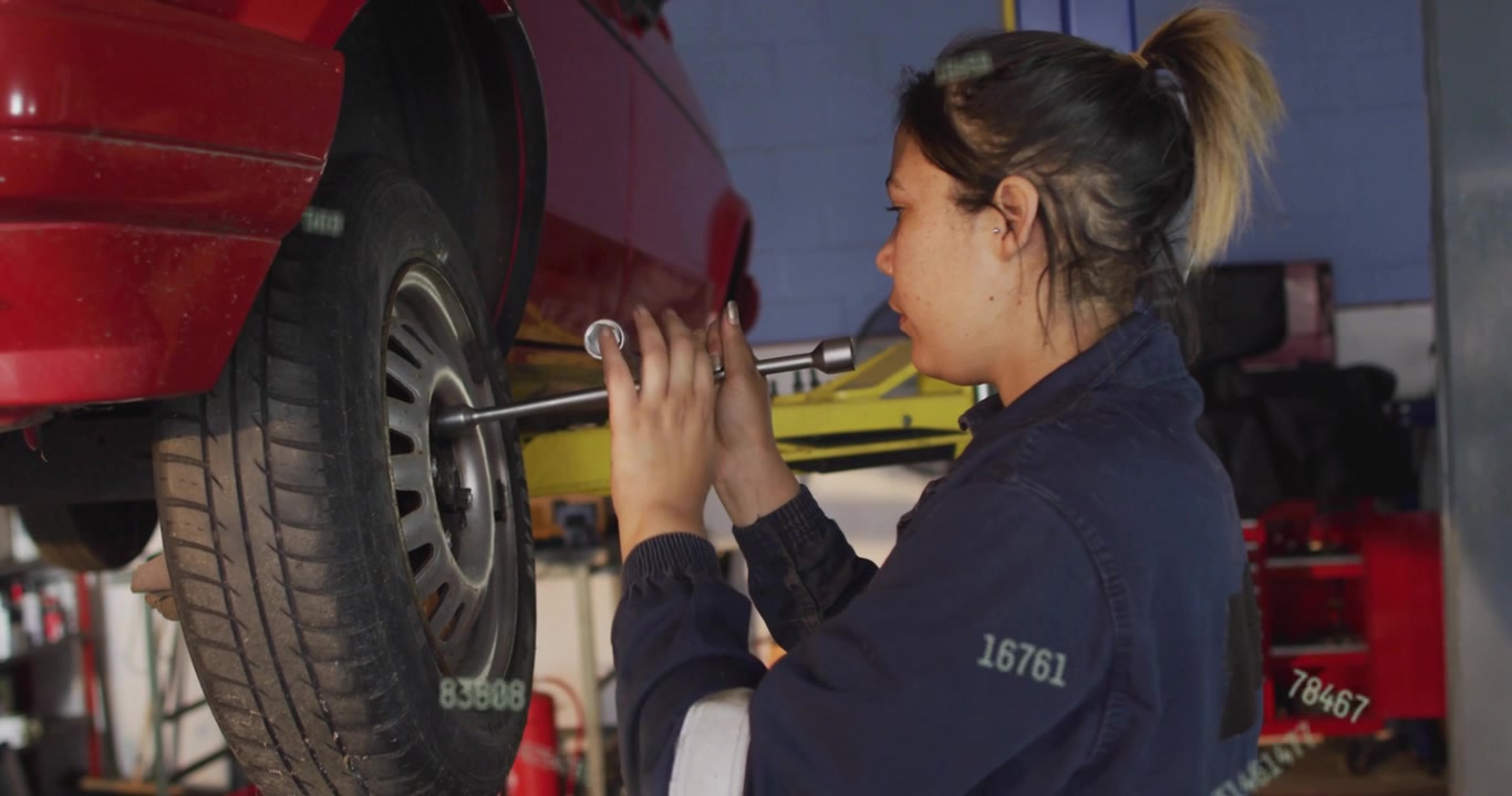 Auto tech placing socket on lug turning wrench loosening nuts for repair text overlays on wrench