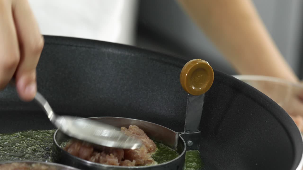 손으로 생 돼지고기를 뜨거운 가스 스토브에 이에 넣고 맛있고 좋은 새를 내기 위해 녹는 버터와 함께 집에서 만든 햄버거를 만드는 재료를 준비합니다.