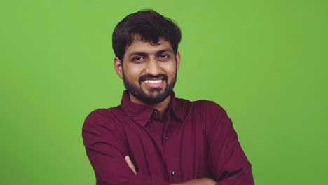 attractive and sexy indian guy looking towards camera and smiles, isolated on green screen