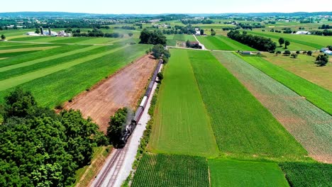 Dampfzug,-Der-An-Einem-Sonnigen-Sommertag-Durch-Amisches-Ackerland-Und-Landschaft-Fährt,-Wie-Von-Der-Drohne-Aus-Gesehen