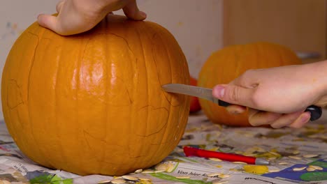calabaza carvin hembra cortando la linda cara de jack o'lantern en calabaza con un cuchillo preparándola como decoración de halloween