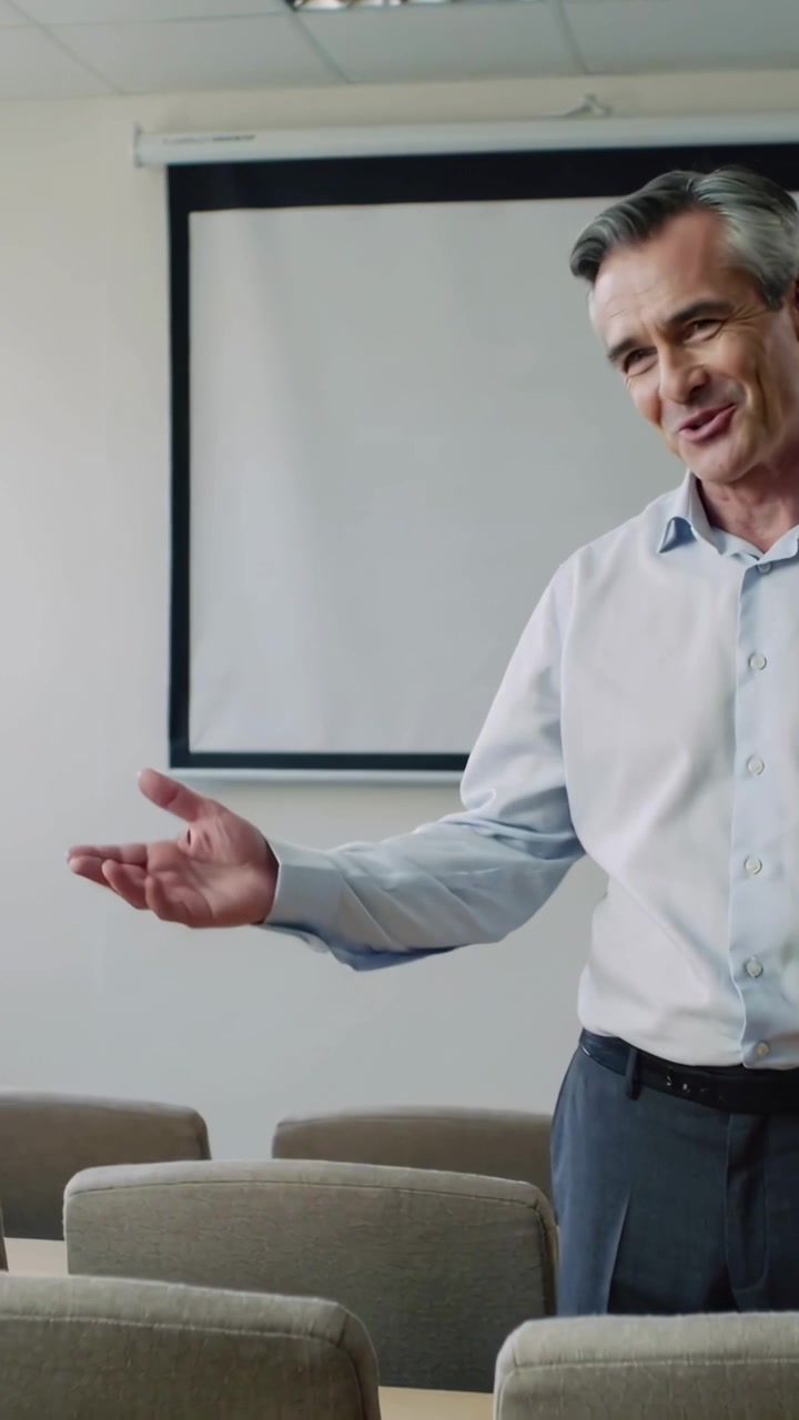 Vídeo vertical: Iniciando reunião, homem falando de forma envolvente na sala de reunião com tela, cadeiras, camisa