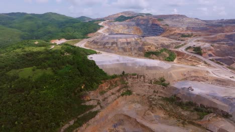 gold and silver mine in green forest landscape of cotui, dominican republic. slow forward wide shot. mountains and hills at mining complex area.