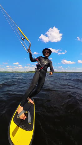 vertical - woman kiteboarding on hydrofoil board in the sea in summer.