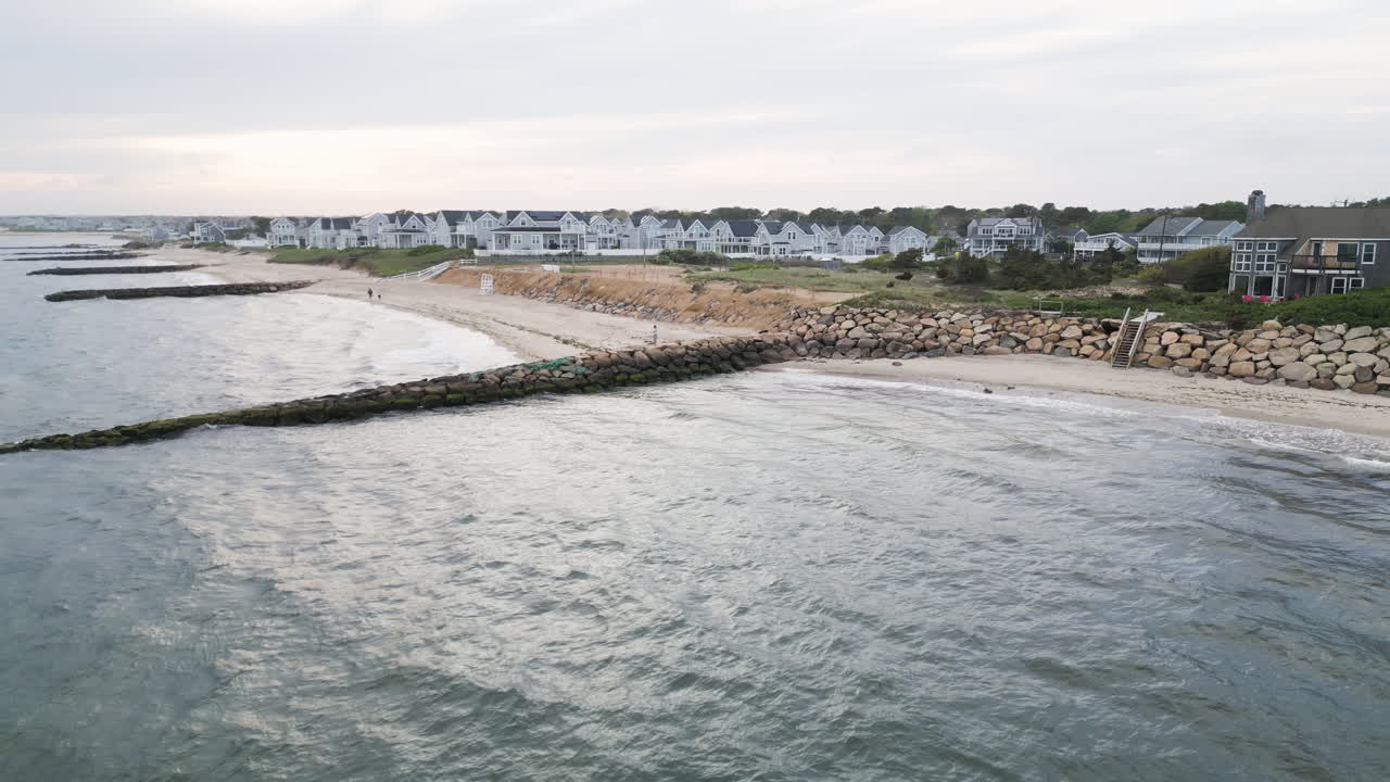 A rocky breakwater and beach houses at sunset in dennis port, nantucket sound, aerial view