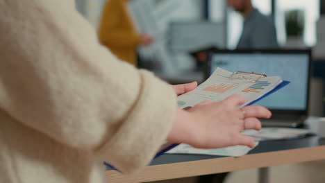 closeup of woman hands holding clipboard with papers looking at pie chart and business profit data