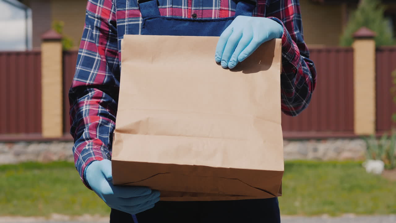 un mensajero con guantes sostiene una bolsa de comida 1