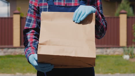 A-Courier-In-Gloves-Holds-A-Bag-Of-Food-1