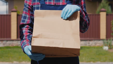 Un-Mensajero-Con-Guantes-Sostiene-Una-Bolsa-De-Comida-1